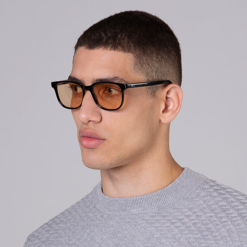 Modelo com rosto tamanho médio usa óculos Carter Black com lente colorida laranja