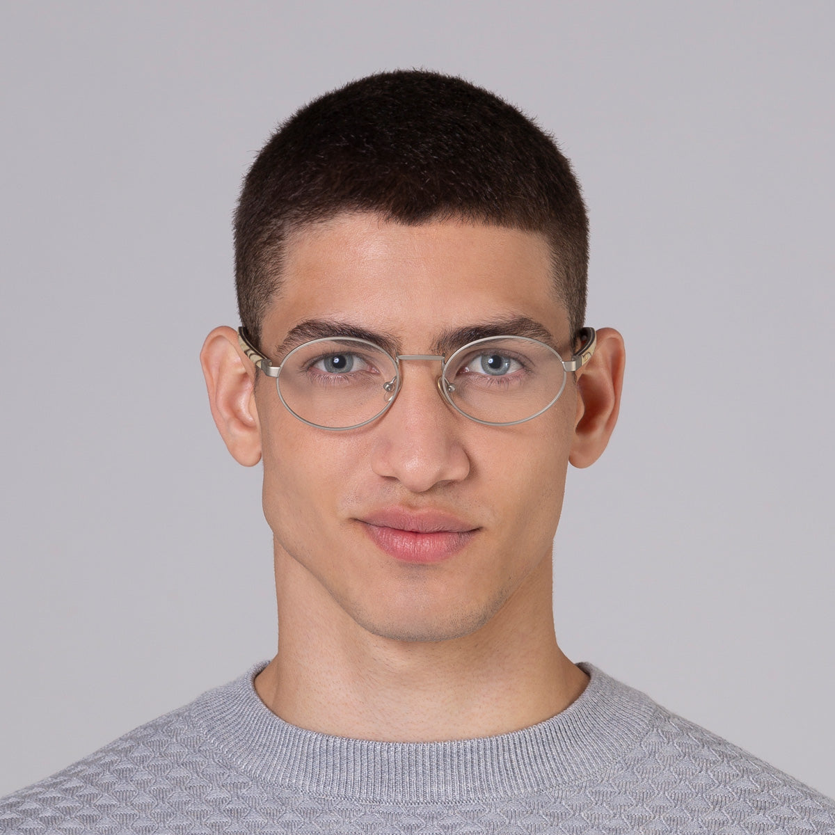 Armação de metal oval prata em modelo com rosto médio.