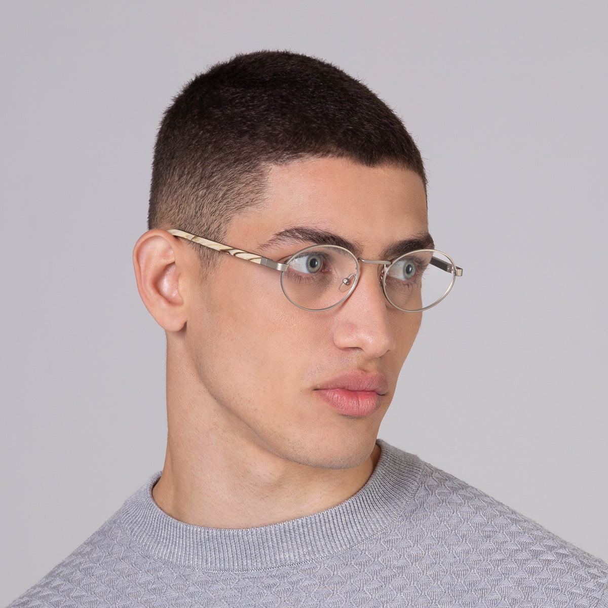 Armação de metal oval prata em modelo com rosto médio.