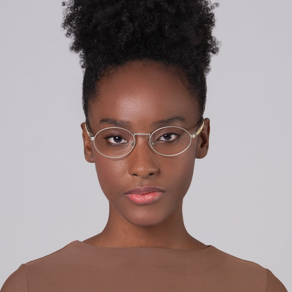 Armação de metal oval prata em modelo com rosto pequeno.