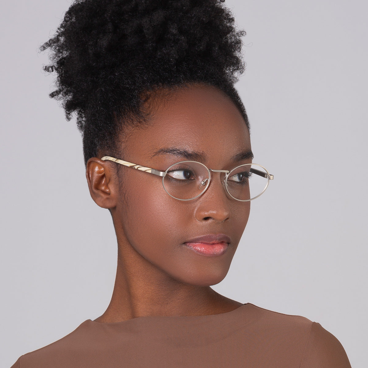 Armação de metal oval prata em modelo com rosto pequeno.