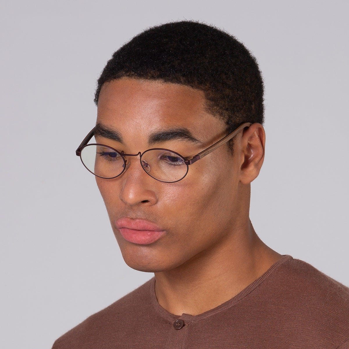 Armação de metal oval vinho em modelo com rosto grande.