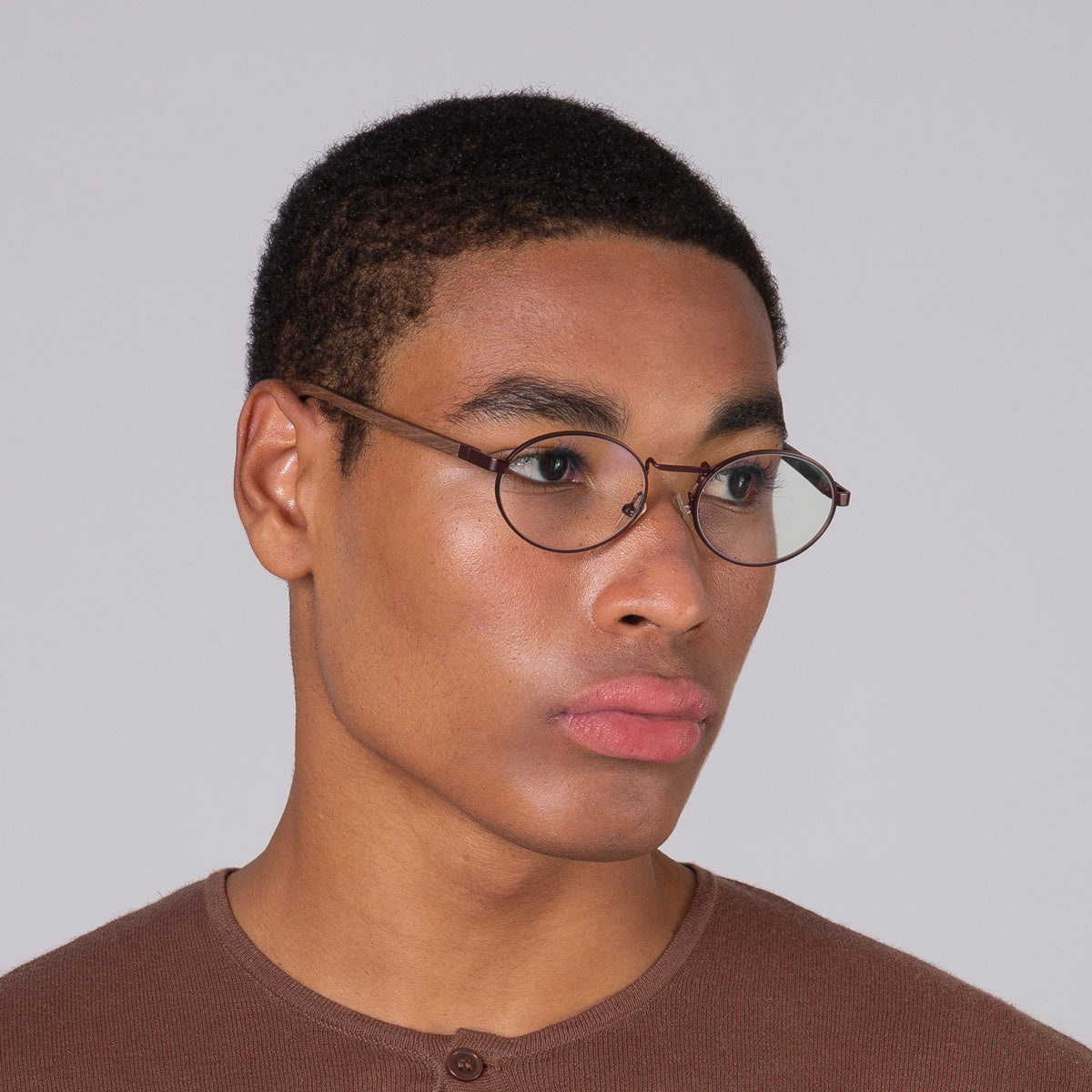 Armação oval vinho em modelo com rosto grande.