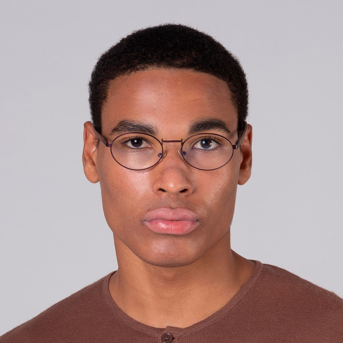 Armação de metal oval vinho em modelo com rosto grande.