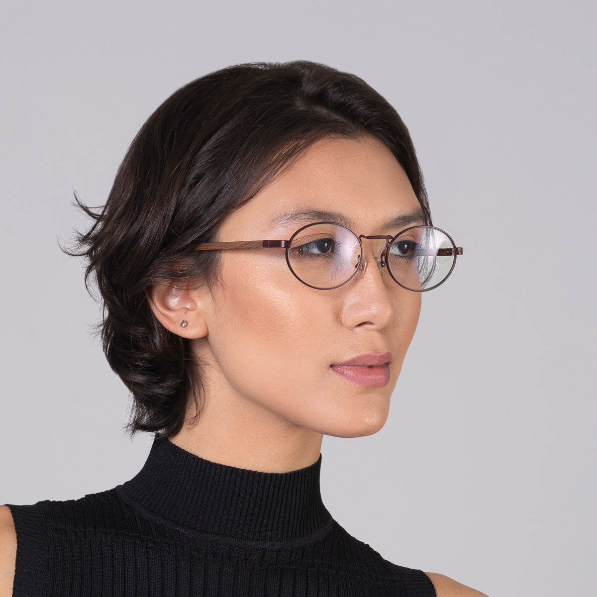 Armação de metal oval vinho em modelo com rosto médio.