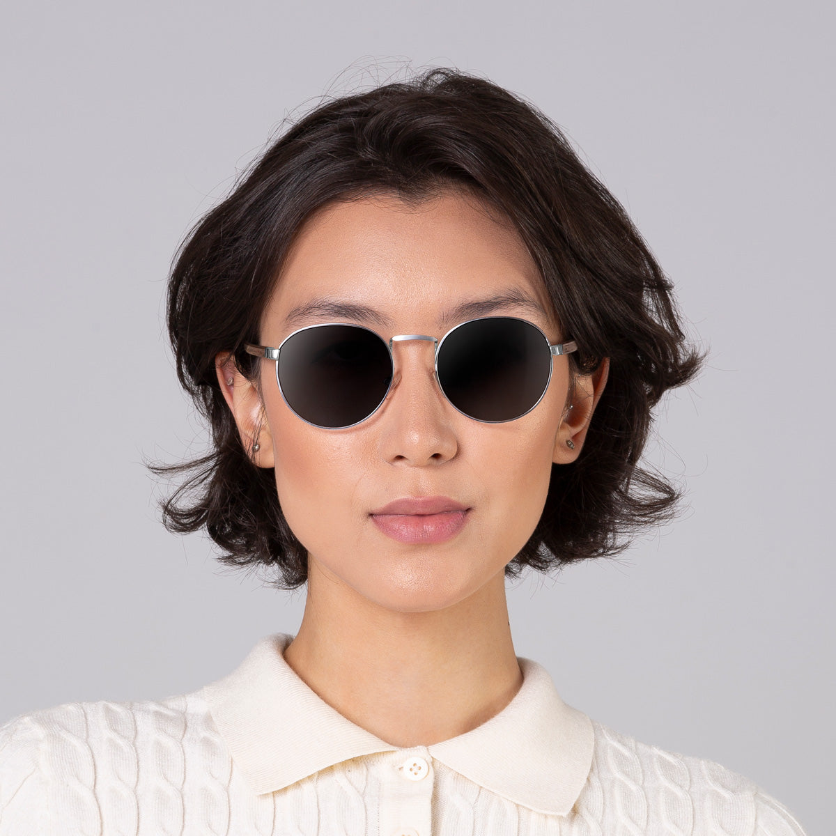 Modelo com tamanho de rosto médio usa óculos redondo médio prata