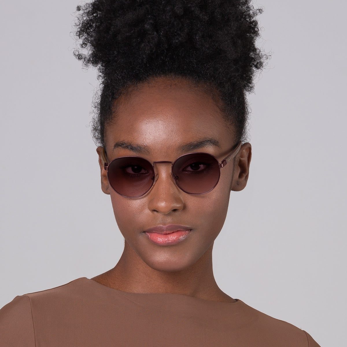 Modelo com tamanho de rosto pequeno usa óculos redondo médio vinho