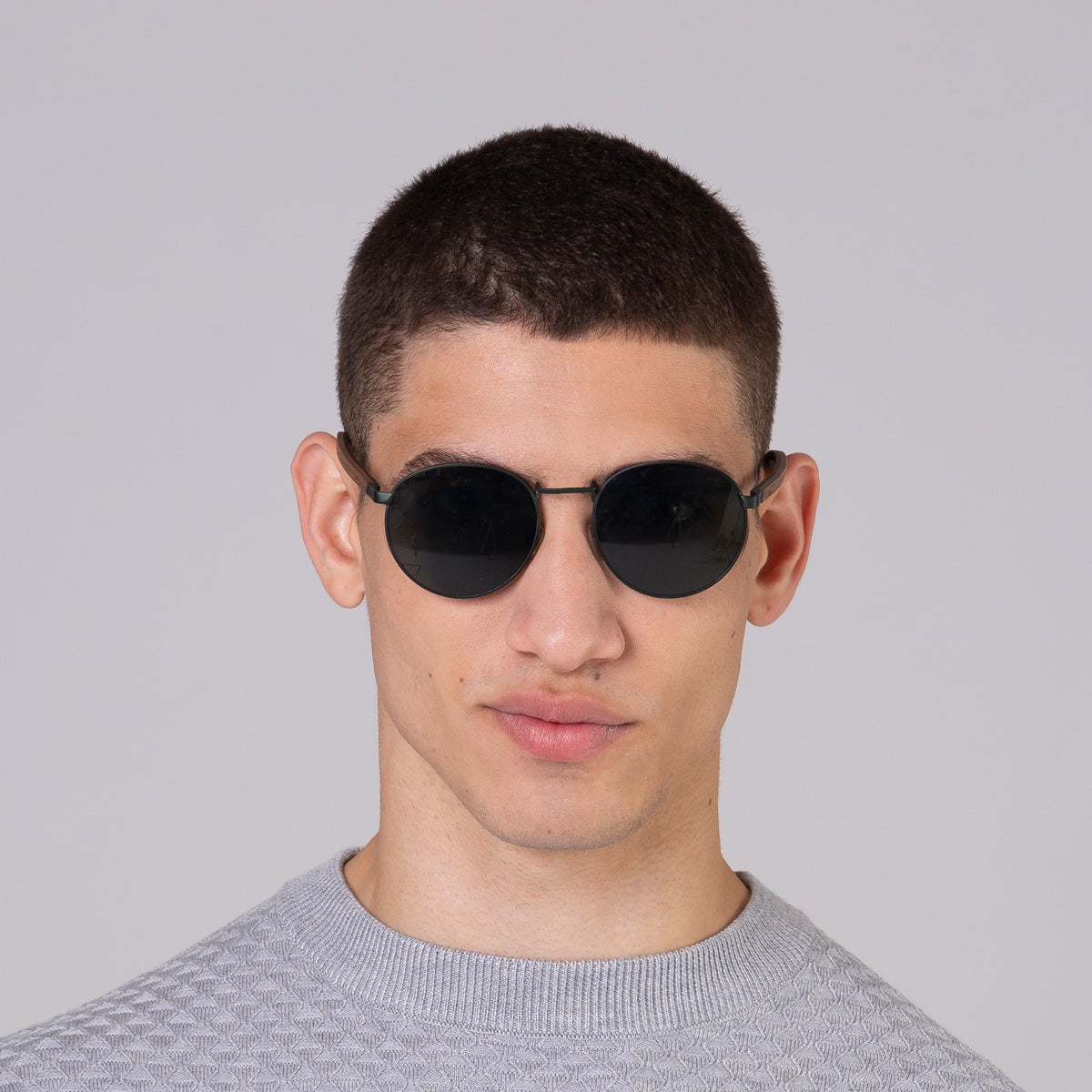 Modelo com tamanho de rosto médio usa óculos redondo médio verde