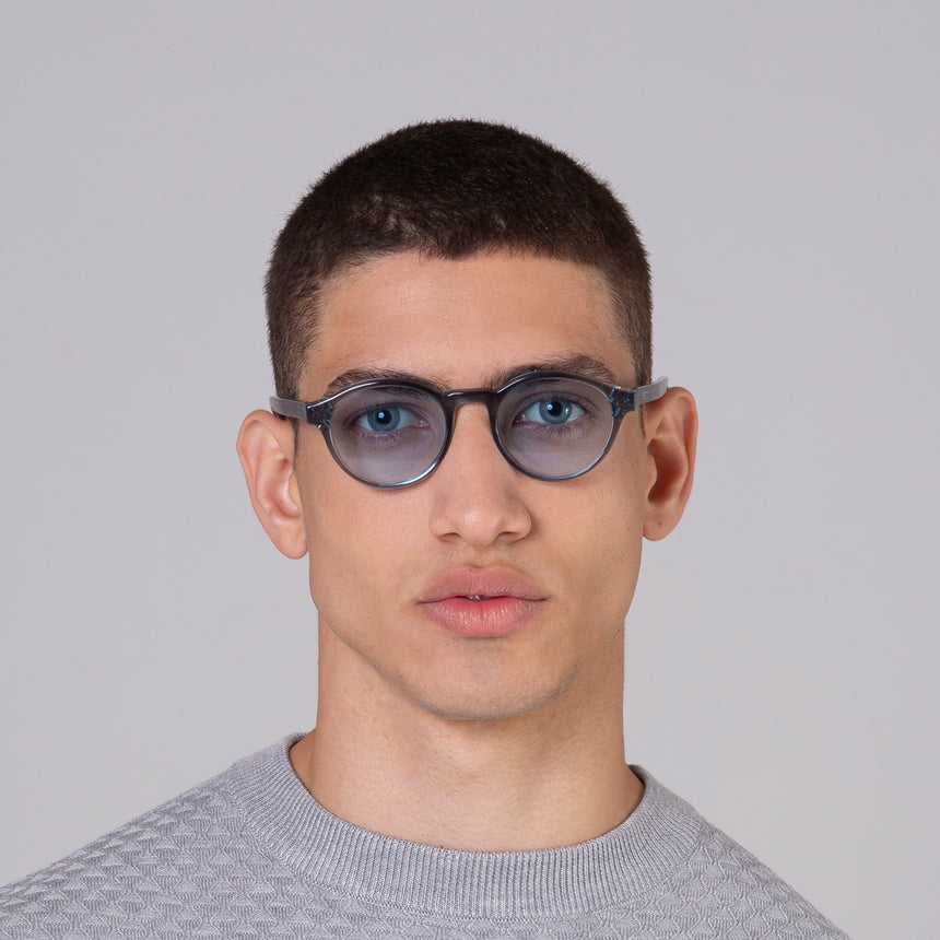 Modelo com rosto tamanho médio usa óculos Nino Sky com lente azul claro
