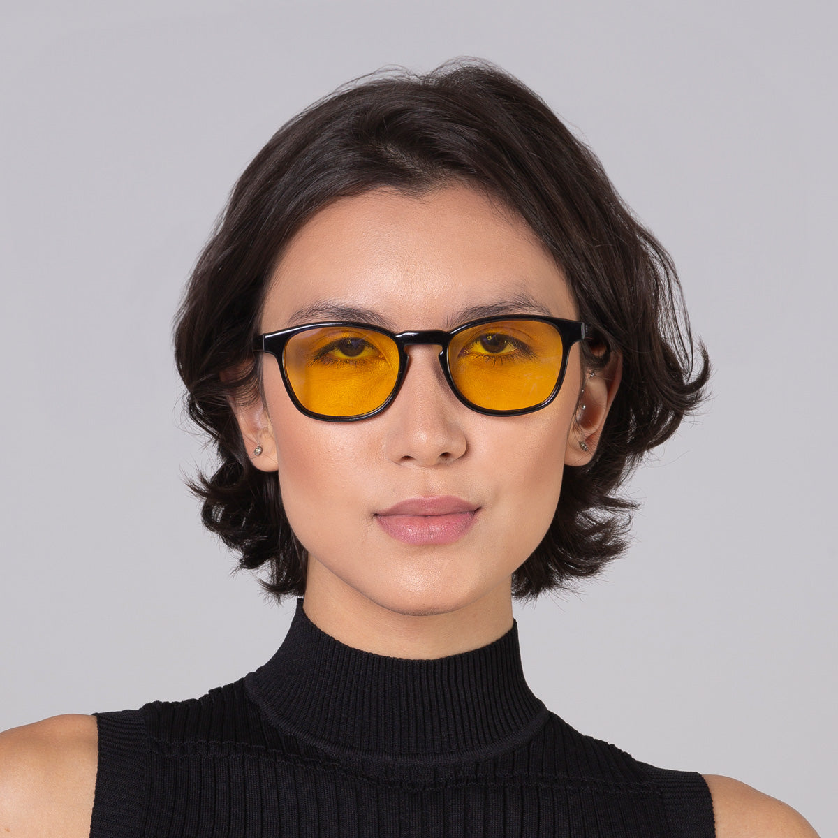 Modelo com rosto tamanho médio usa óculos Olli Black com lente amarela