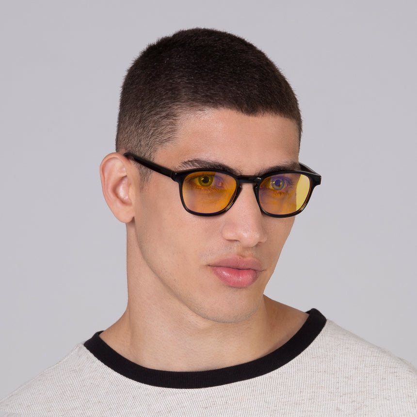 Modelo com rosto tamanho médio usa óculos Olli Black com lente amarela