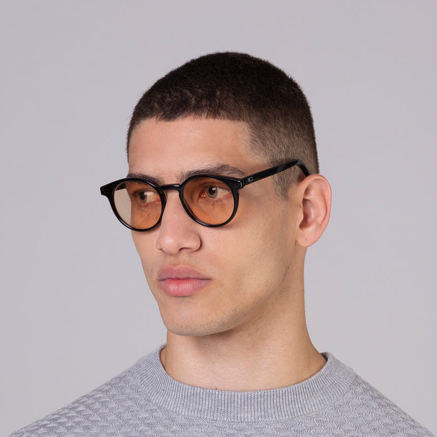 Modelo com rosto tamanho médio usa óculos Taylor Black com lente colorida laranja