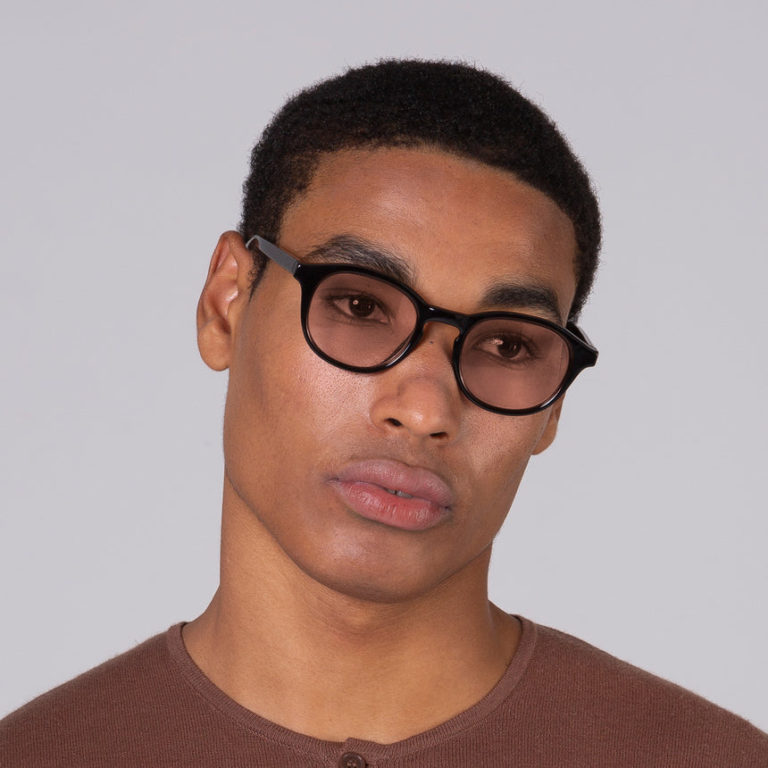 Modelo com rosto tamanho grande usa óculos Toshi Black com lente colorida ambar